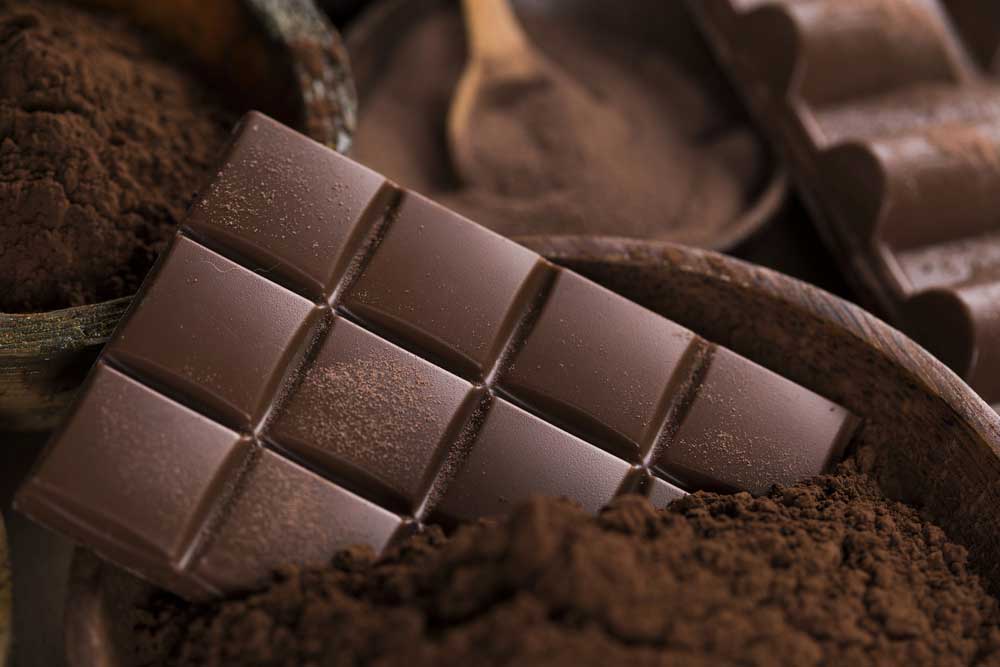 Dark chocolate bar on cocoa powder